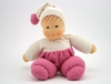 La poupée Nanchen en tissu éponge blanc et rose est assise.