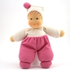 La poupée en tissu éponge blanc et rose se tient debout.