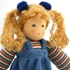 Close up sur le visage d'une poupée de chiffon aux yeux bleus et aux cheveux blonds portant un sweat rayé et une robe de velours bleu.