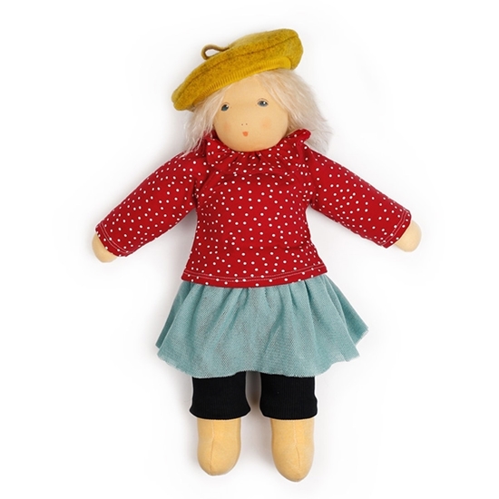 Grote Nanchen pop met halflang blond mohair haar en blauwe ogen in een blauwe geribbelde broek, een lichtblauwe tule rok, een rode sweatshirt met witte stippen en bijpassende kraag en een mosterdkleurige wollen baret.
