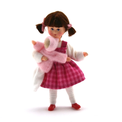 Kleine poppenhuispop Erna Meyer Lisa met donkerbruin haar in 2 staartjes, blauwe ogen, een witte trui en maillot, een donkerroos geruit kleedje en een popje in haar armen.