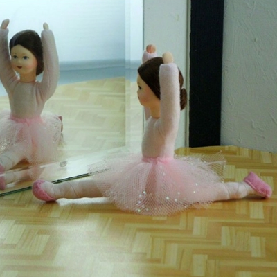A flexible Erna Meyer doll with pink tutu and pink ballet shoes is looking in the mirror while doing the splits.