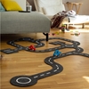 28 pièces de feutrine noire forment un circuit pour jouer avec deux petites voitures en bois dans le salon.