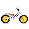 Wooden balance bike with yellow wheels, white and black striped frame, like a zebra, in low position and an adjustable saddle.