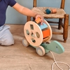 Un petit enfant joue avec une tortue en bois à tirer qui est aussi un trieur de fomes.