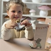 Little girl plays with a small teddy bear in front of his wardrobe with teddy bear clothes.