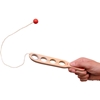 Une main tient une latte en bois perforée de 4 trous et reliée à une petite balle rouge en bois qu'elle tente d'attraper dans l'un des trous.
