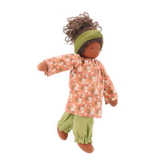 Nanchen pop 40 cm met bruine huid, bruine ogen en bruin krulhaar, abrikooskleurig kleedje, lichtgroene lange broek en lichtgroene haarband.