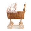 Rieten poppenwagen met zacht roze bekleding bedrukt met kleine paddestoelen.