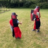 Deux enfants jouent au chevalier normand avec des boucliers de viking.